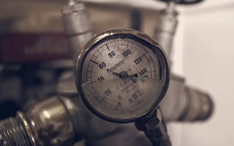 Close-up of a refrigerant pressure gauge mounted on a brass pipe fitting